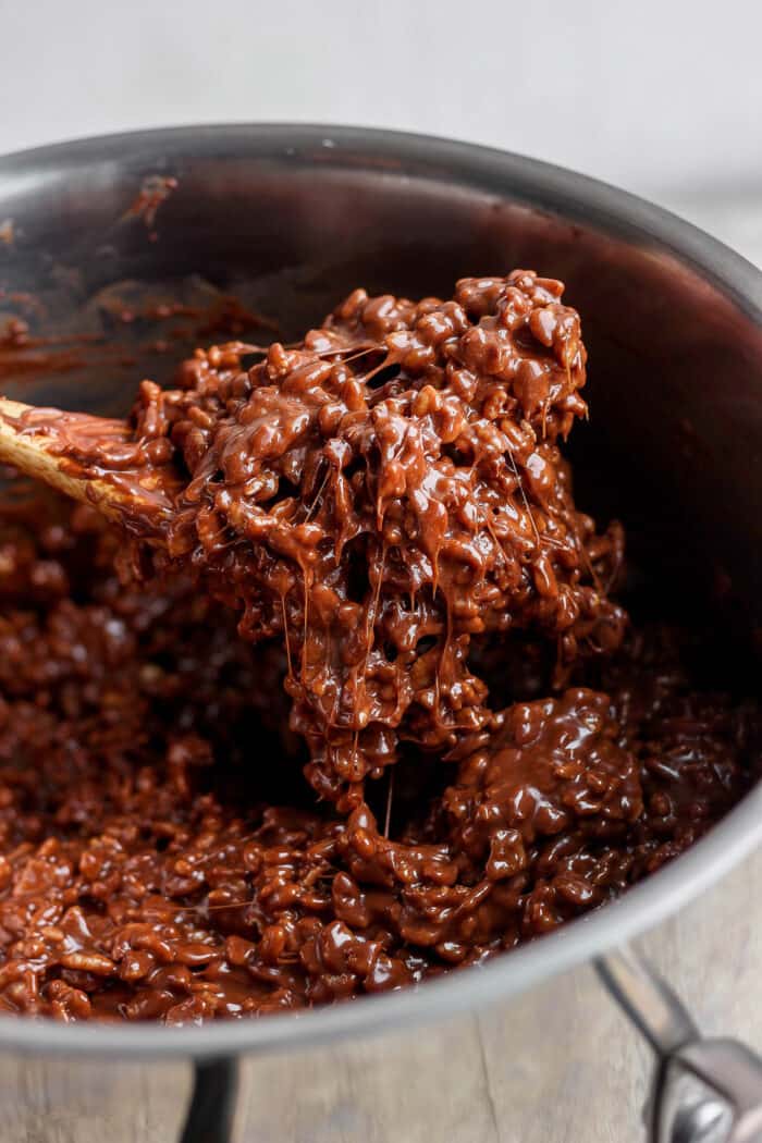 A spoon lifts out a scoop of chocolate-coated rice krispies.