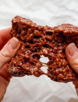 A hand pulls apart a chocolate rice krispie treat.