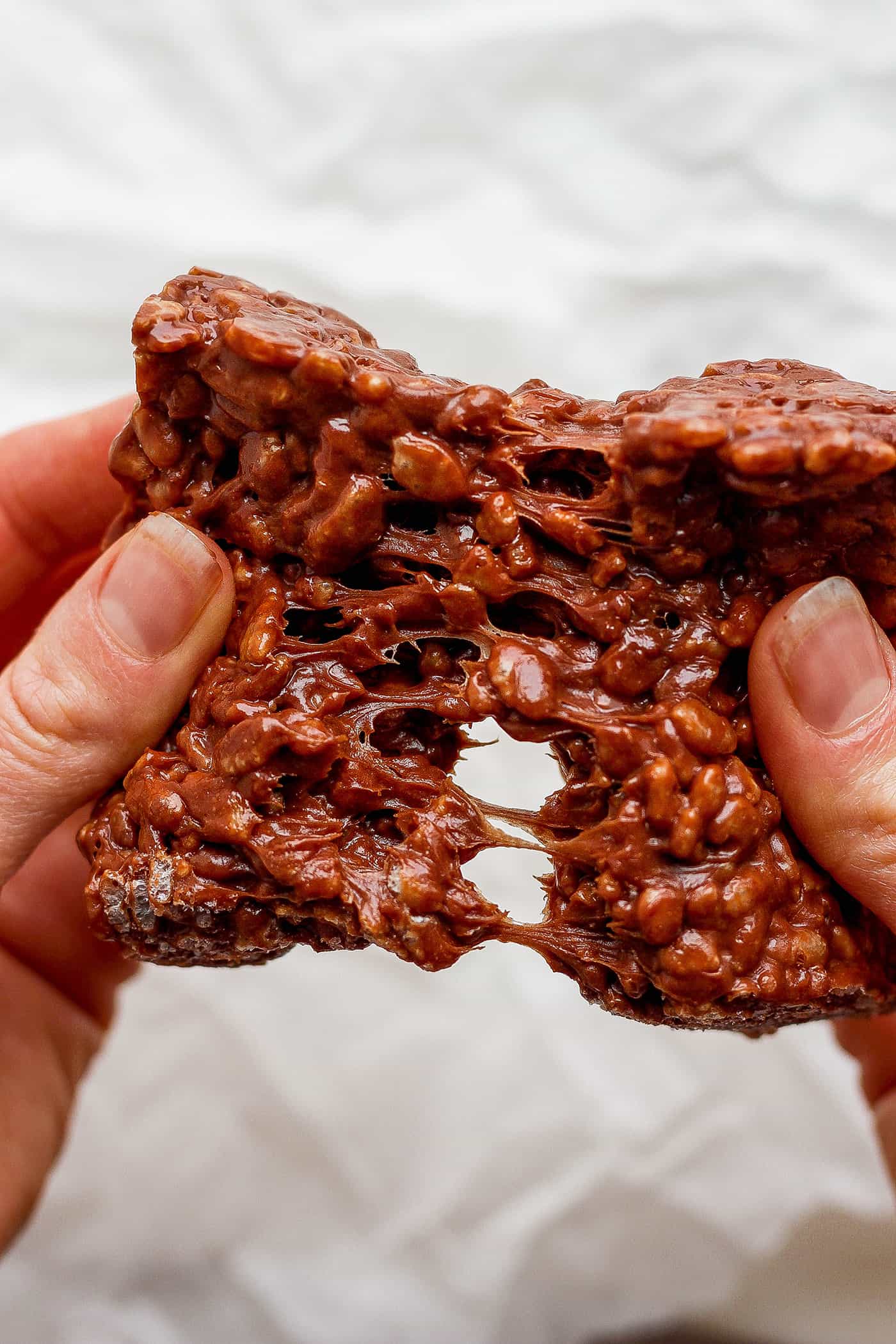 A hand pulls apart a chocolate rice krispie treat.