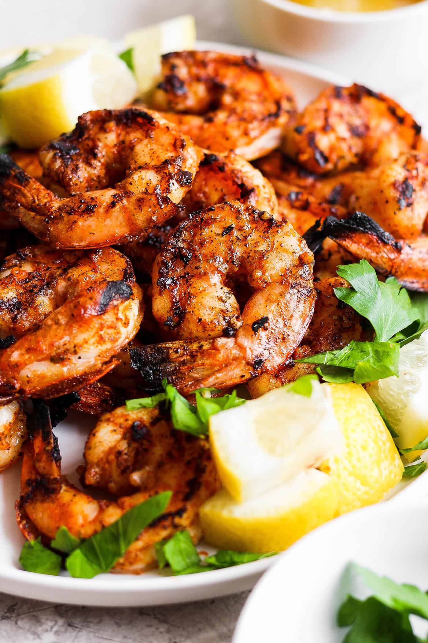 A close up of a platter of grilled shrimp and lemon wedges.