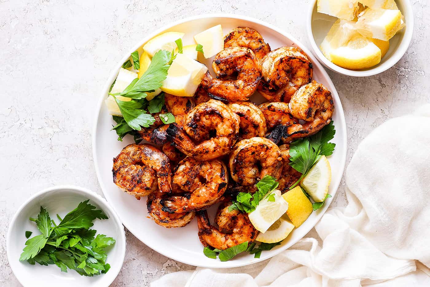 A platter of grilled shrimp surrounded by lemon wedges.