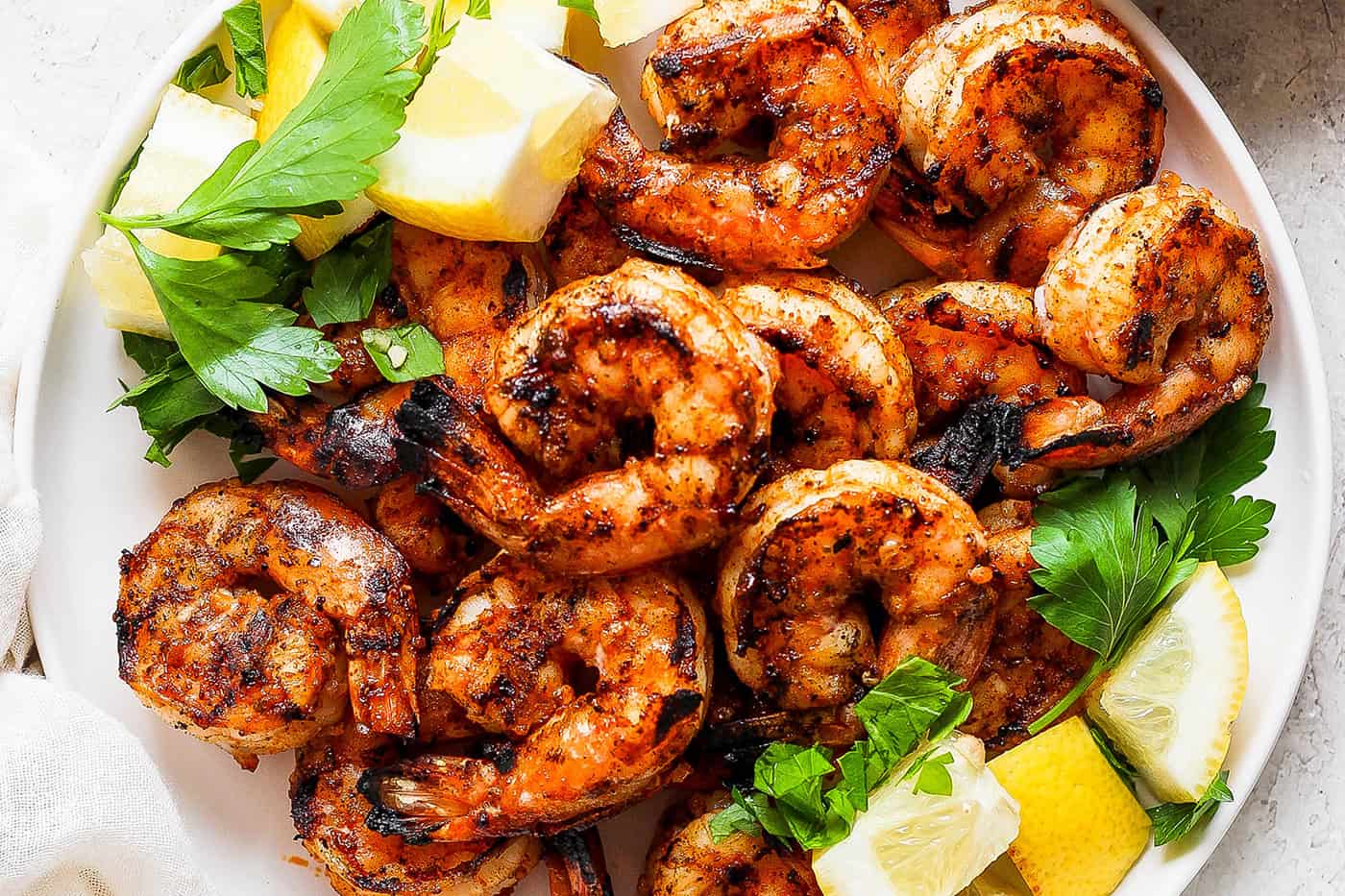 A close up of a platter of grilled shrimp and lemon wedges.