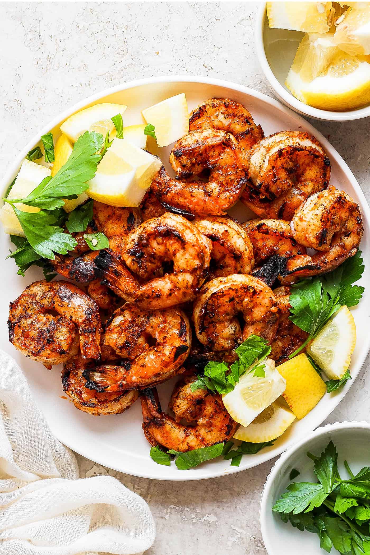 A platter of grilled shrimp surrounded by lemon wedges.