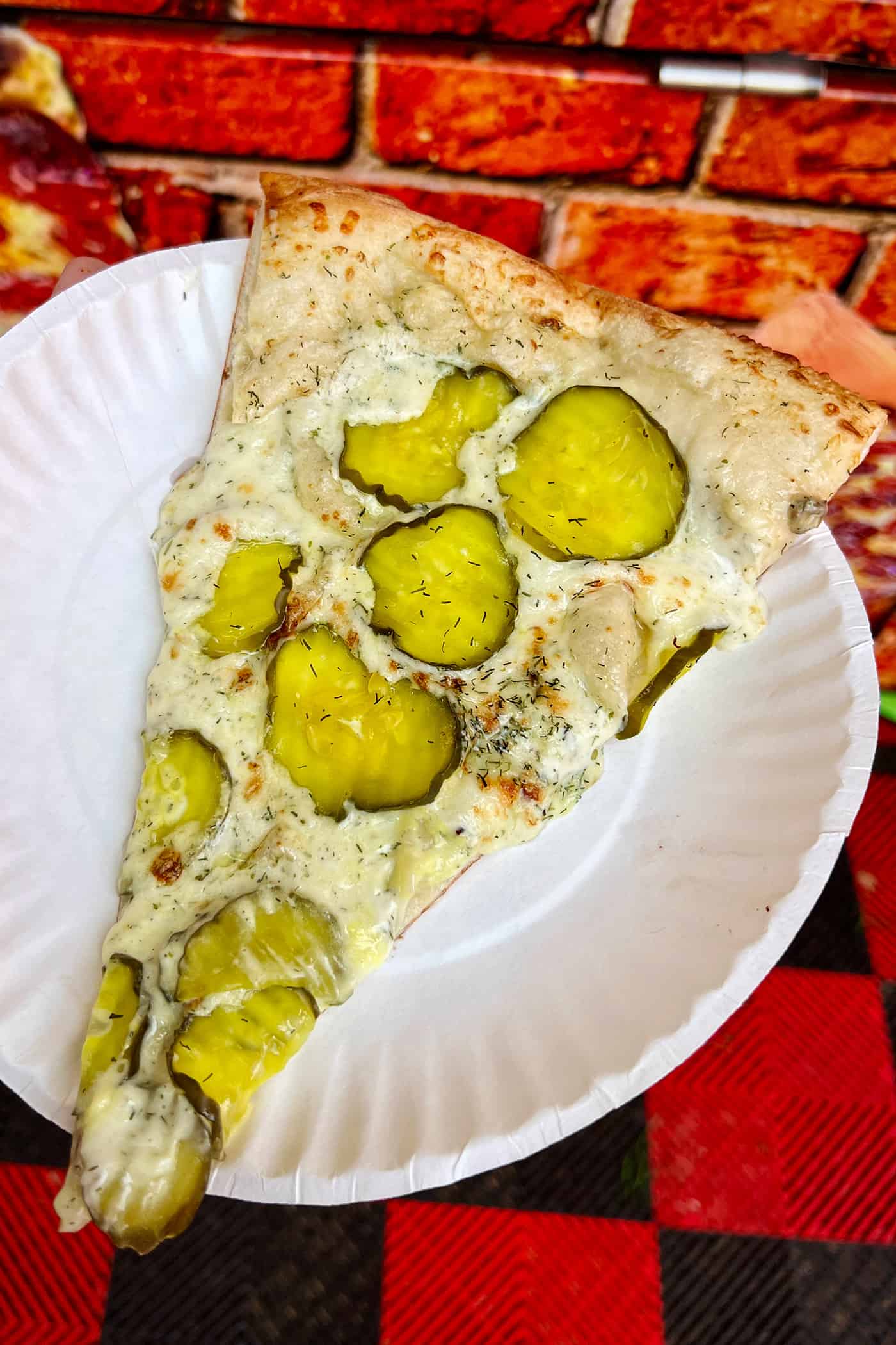 pizza with pickles on a white paper plate