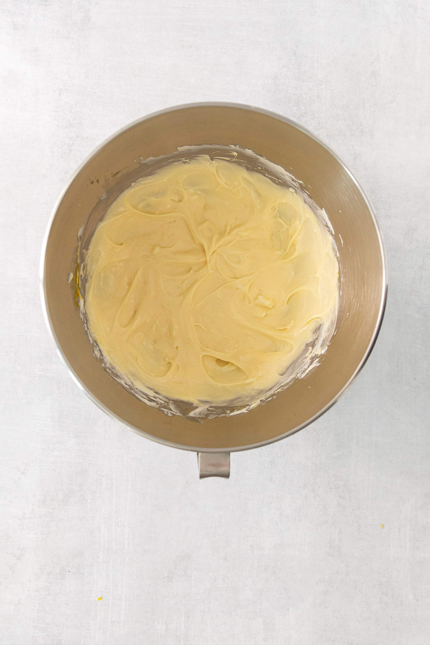 A mixing bowl is shown full of cheesecake filling.