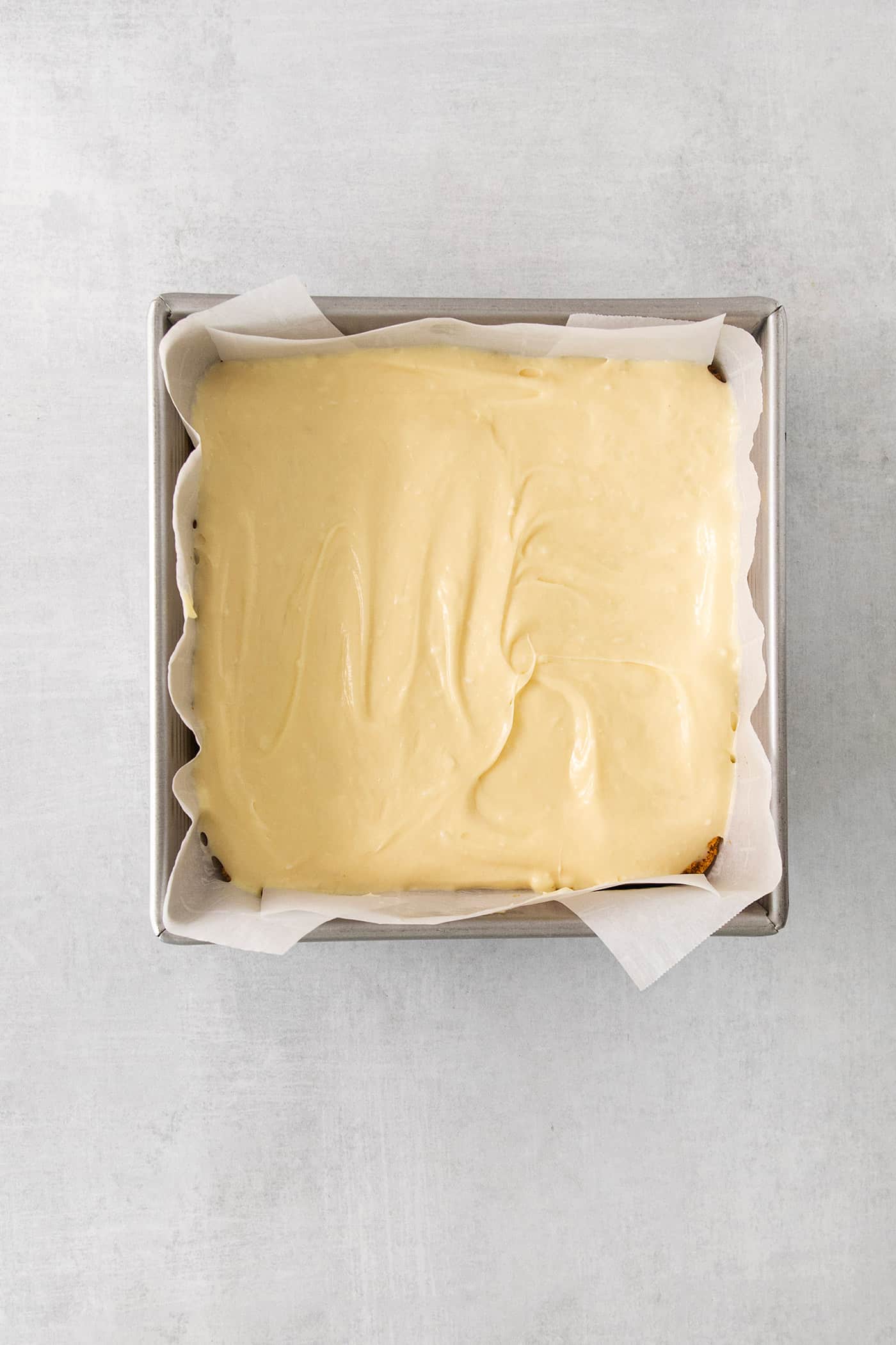 Cheesecake filling is spread in square baking pan.