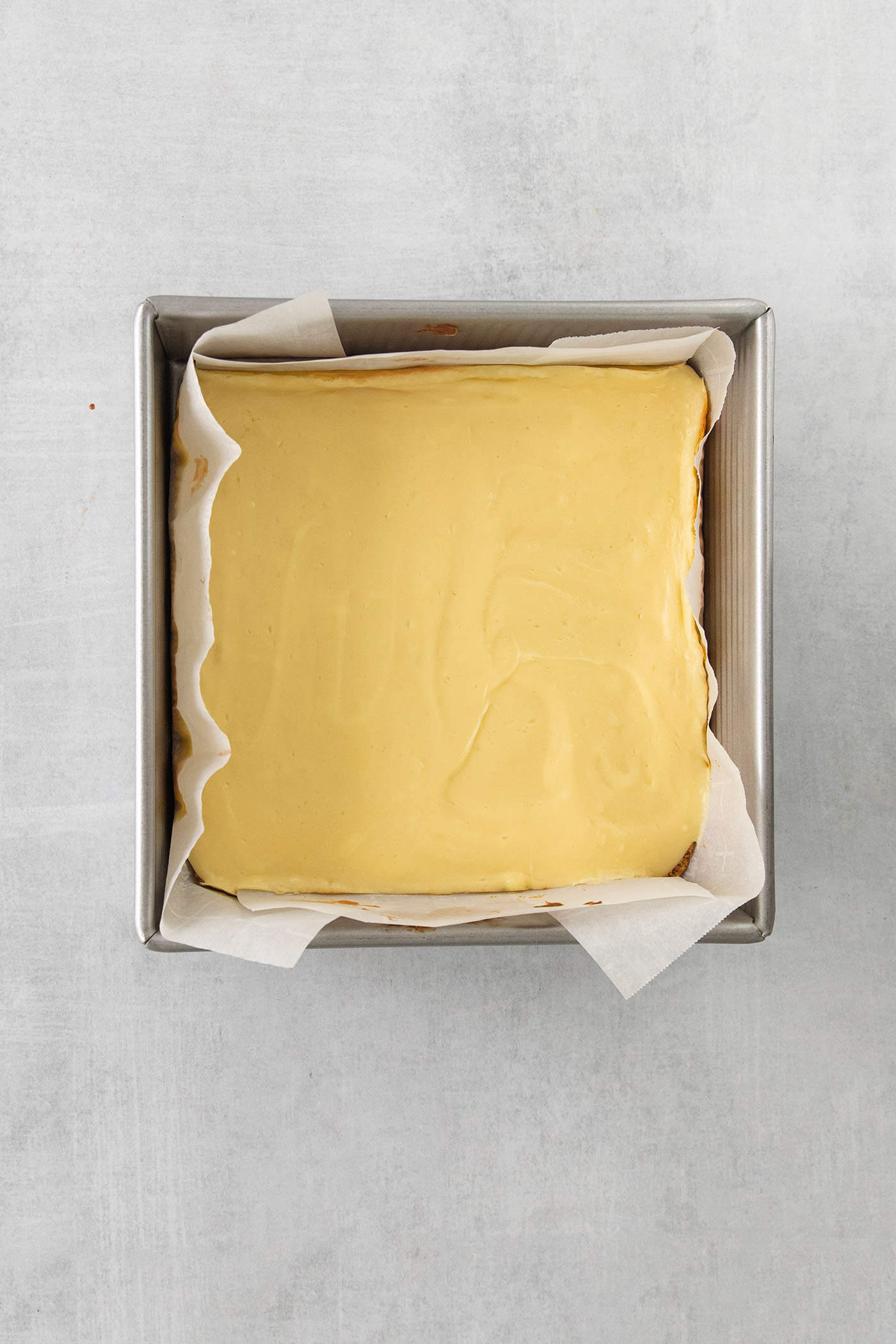 Cheesecake filling is spread in square baking pan.