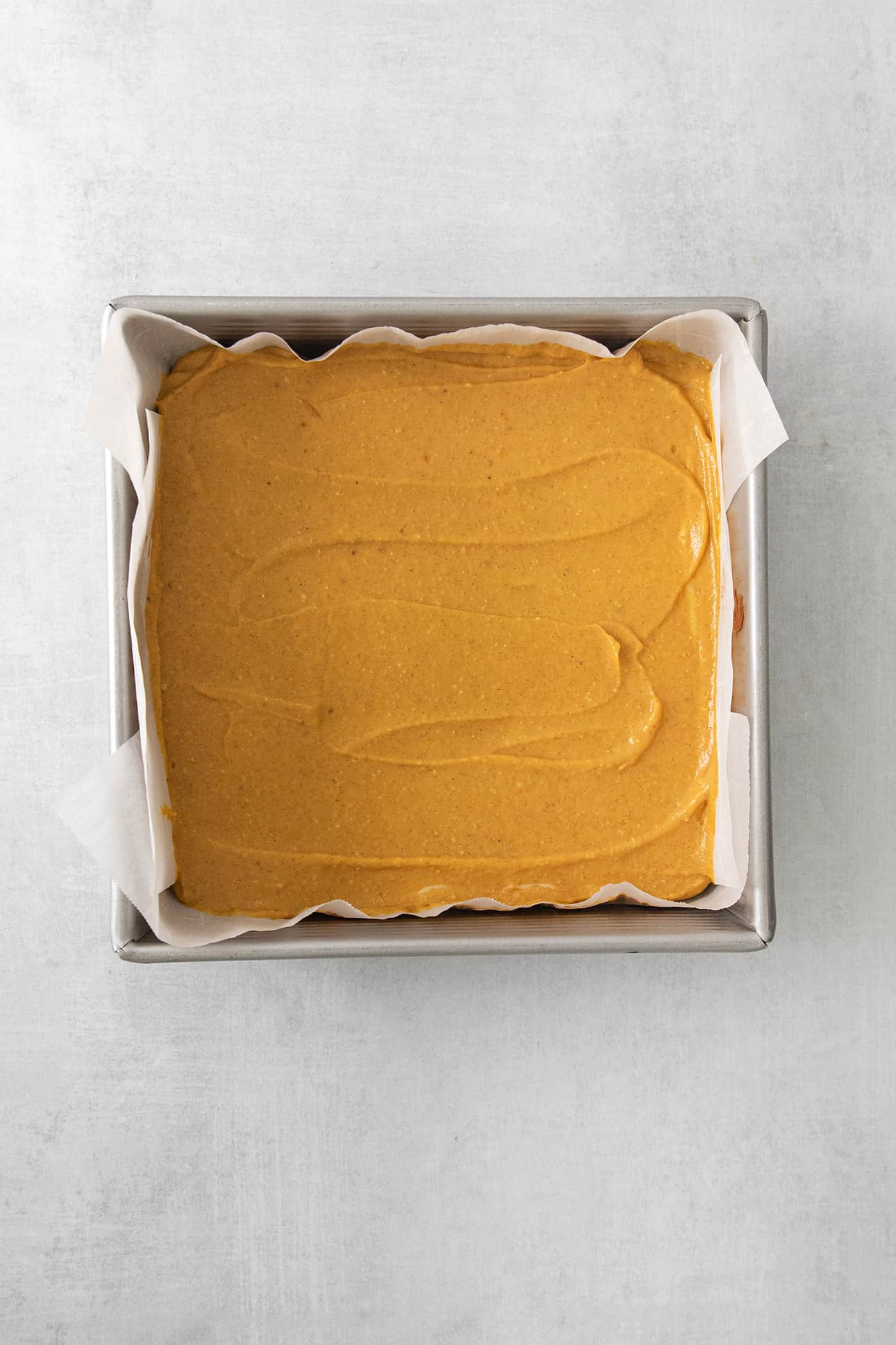The pudding layer is spread on top of cheesecake in a square baking pan.