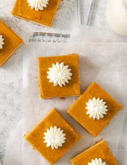 A top down shot of pumpkin cheesecake bars on a white background.