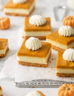 Pumpkin cheesecake bars are shown on a white backgrounf.