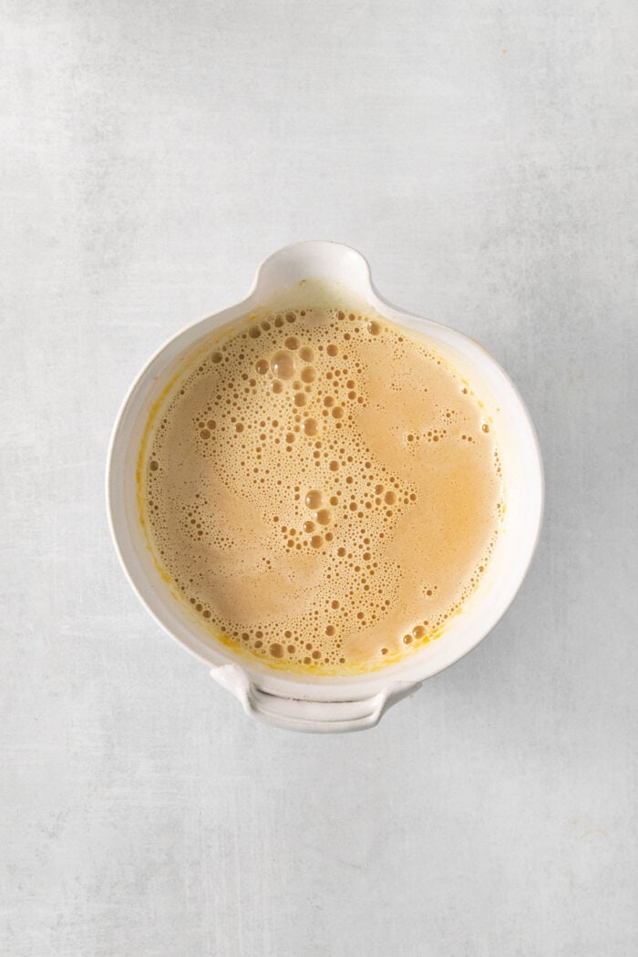 A foamy bowl of pumpkin custard is shown on a white background.