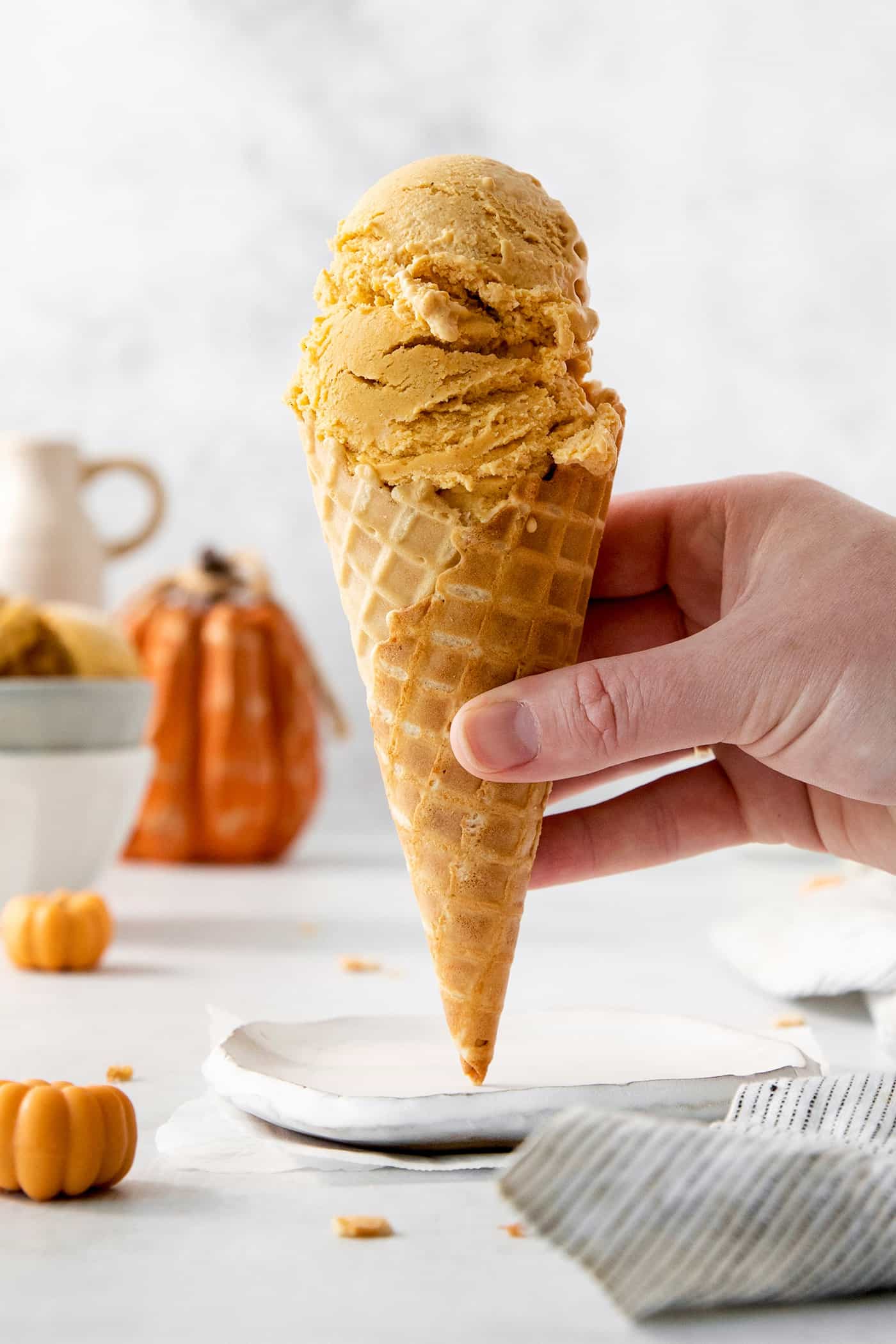 A hand holds a cone of pumpkin ice cream.