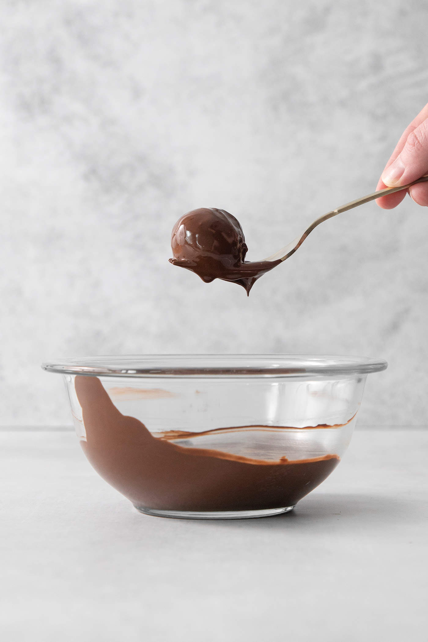 A fork holds a pumpkin pie truffle that has been dipped in dark chocolate.