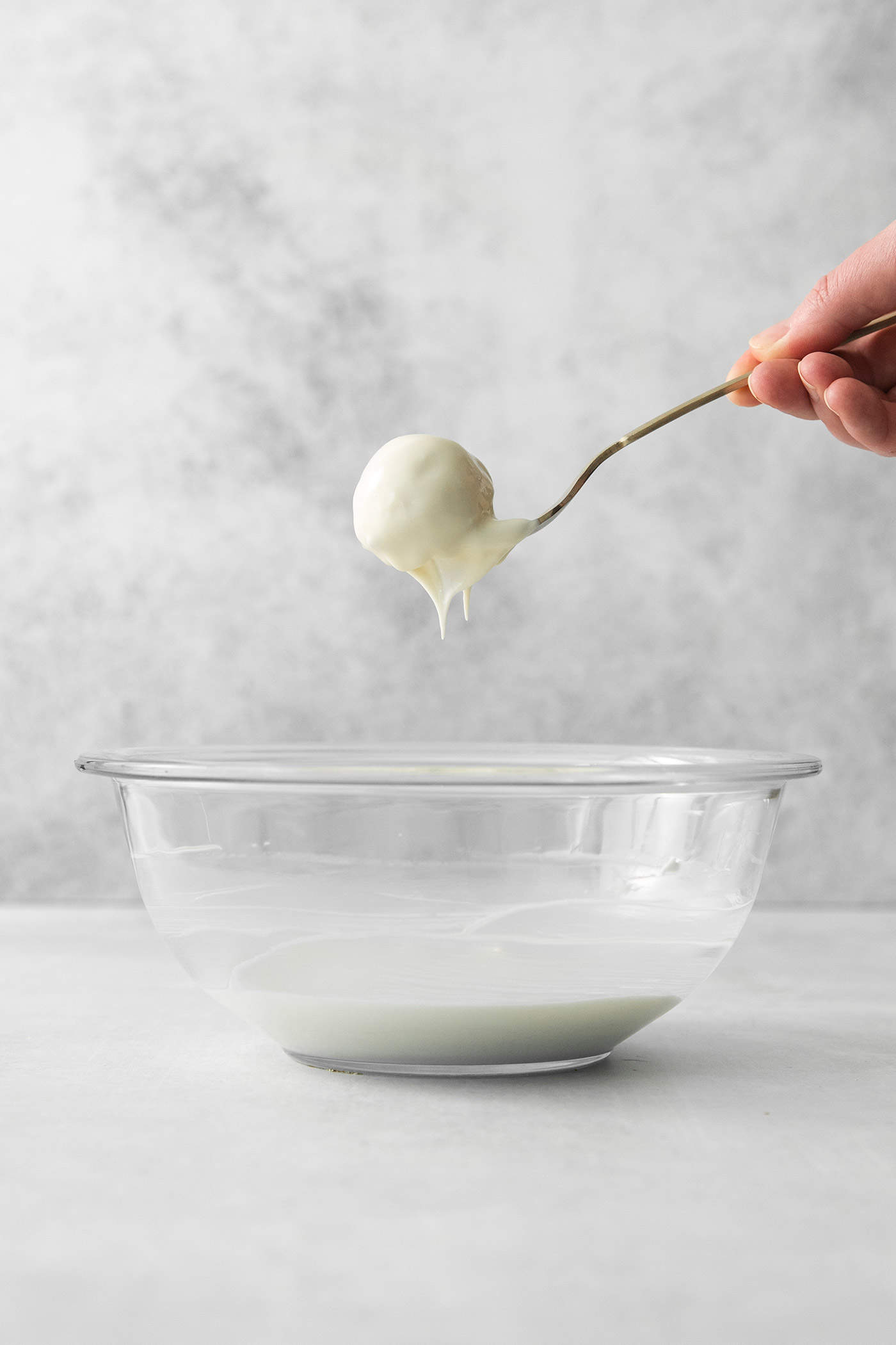 A fork holds a pumpkin pie truffle that has been dipped in white chocolate.