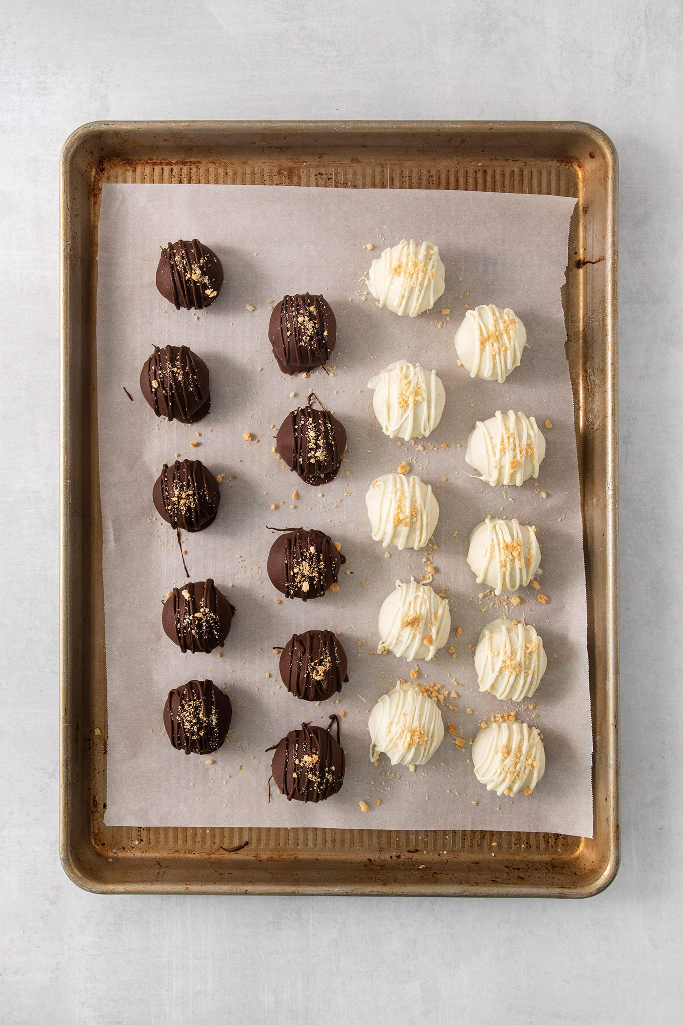 A baking tray holds pumpkin pie truffles, some covered with white chocolate and some covered with dark chocolate.