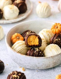 A white bowl of pumpkin pie truffles is shown on a white background.