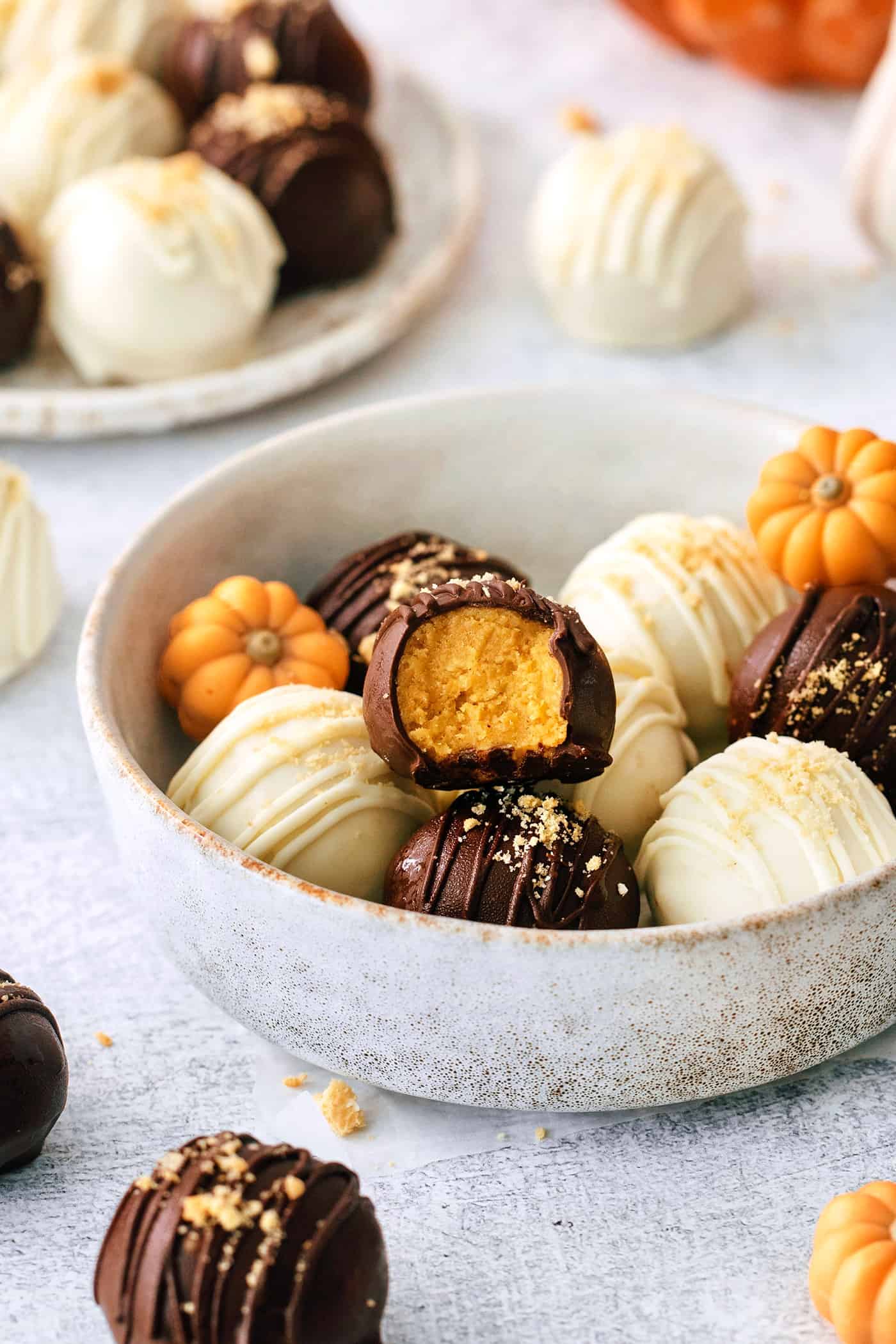 A white bowl of pumpkin pie truffles is shown on a white background.