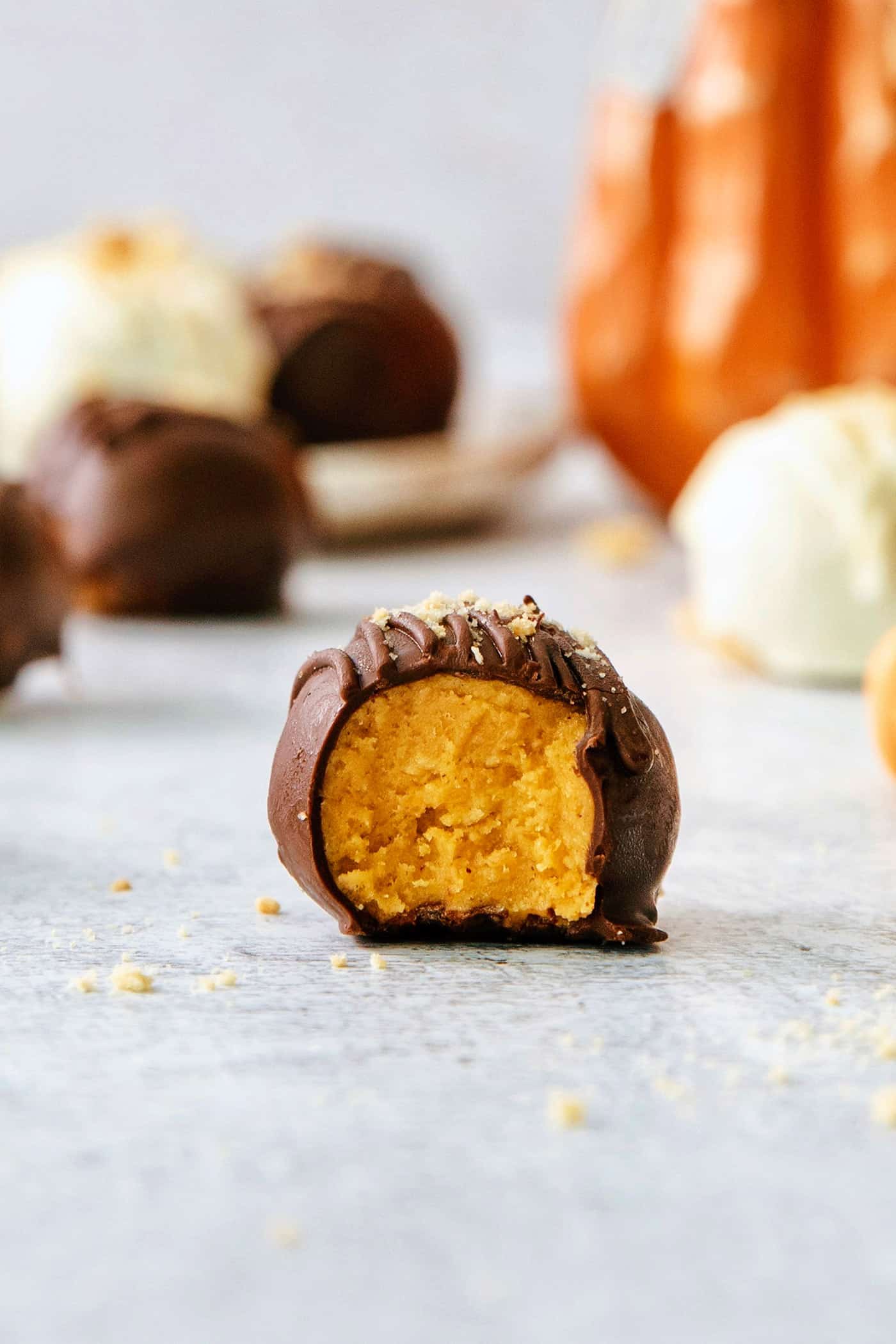 A chocolate covered pumpkin pie truffle is shown with a bite taken out of it.