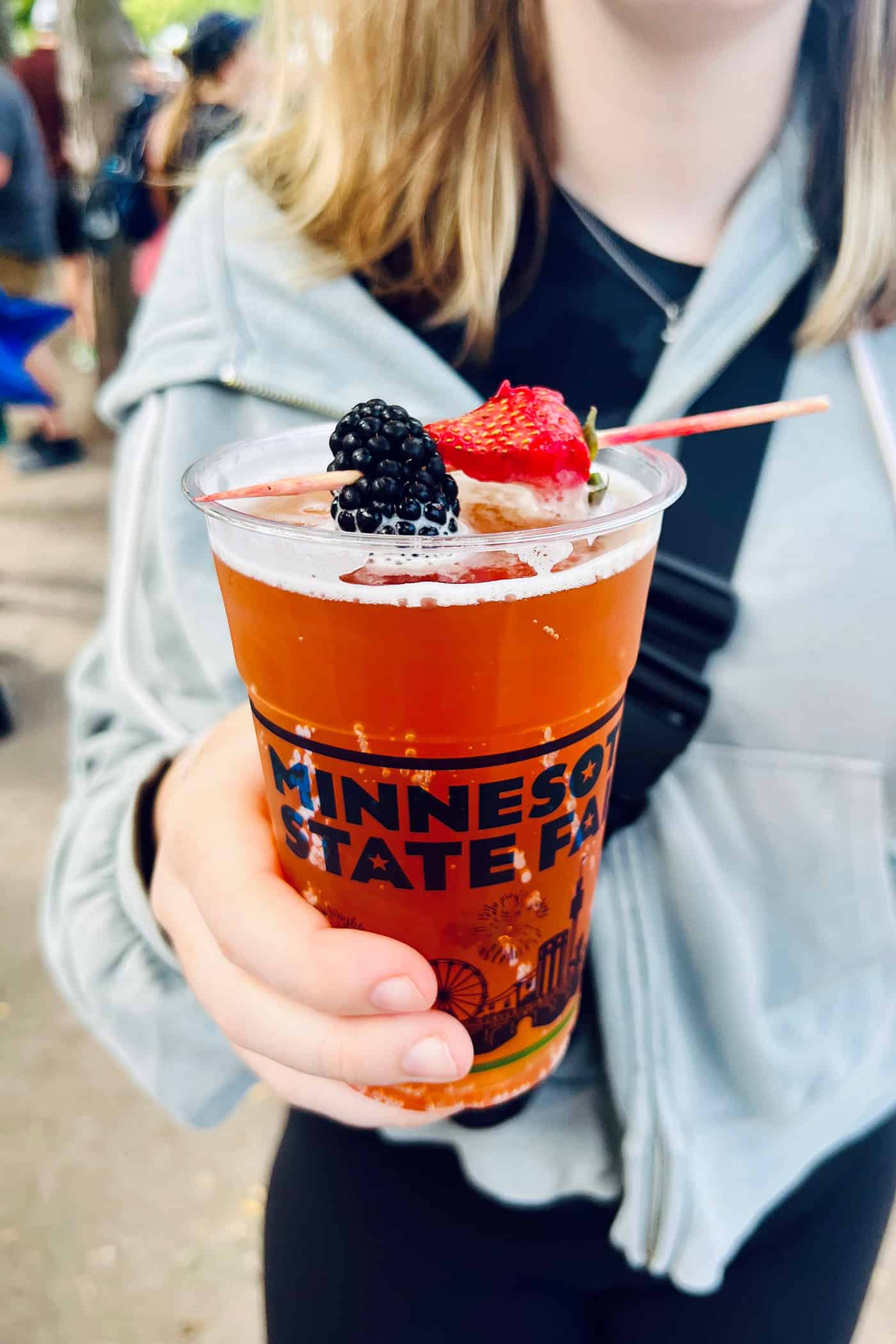 a shandy style beer with a skewer of blackberry and strawberry