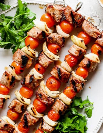 Honey mustard beef kabobs are shown together on a white plate.