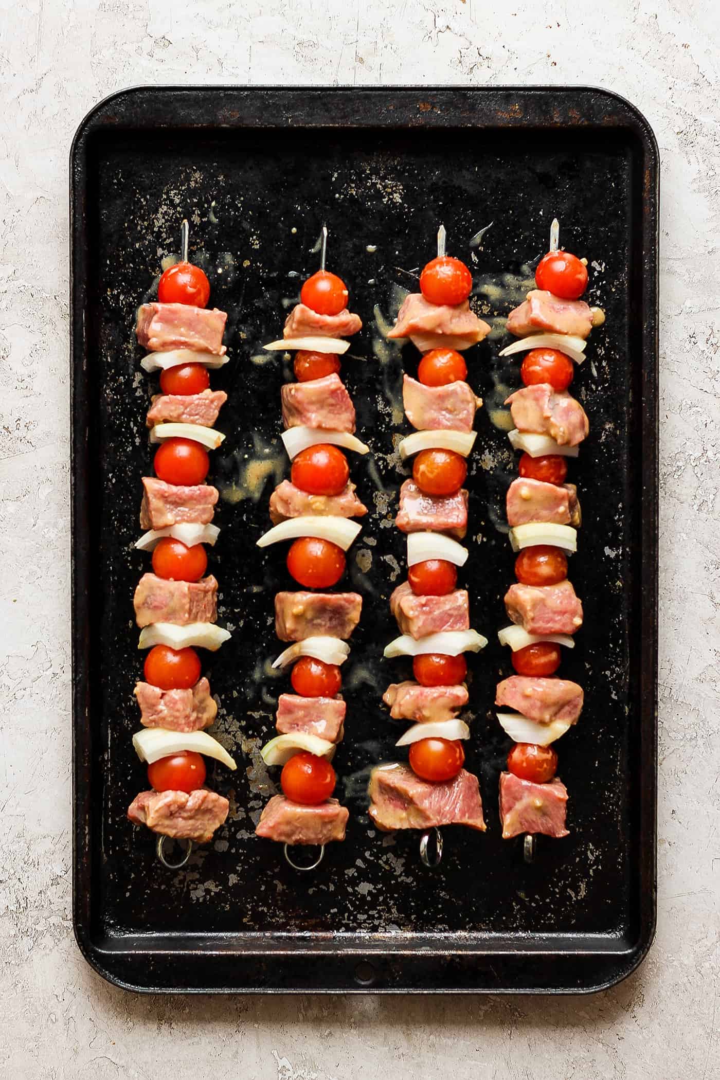 Skewers of honey mustard beef kabobs with vegetables are shown cooking on a grill.