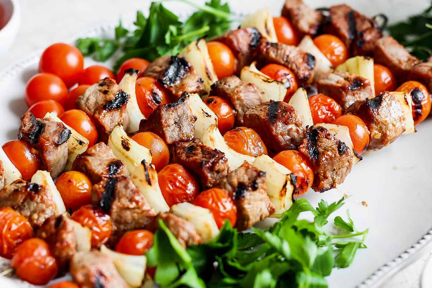 Honey mustard beef kabobs are shown together on a white plate.