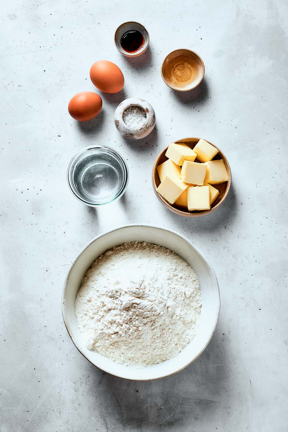 Ingredients to make pastry dough are shown: eggs, vanilla paste, sugar, butter, vinegar.