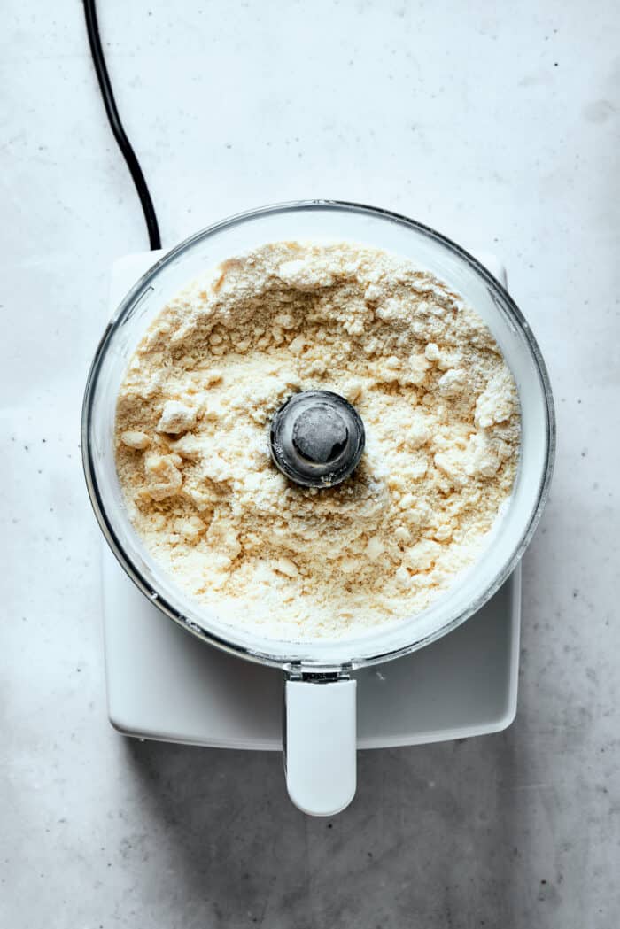 A crumbly pastry dough mix is shown in a food processor.