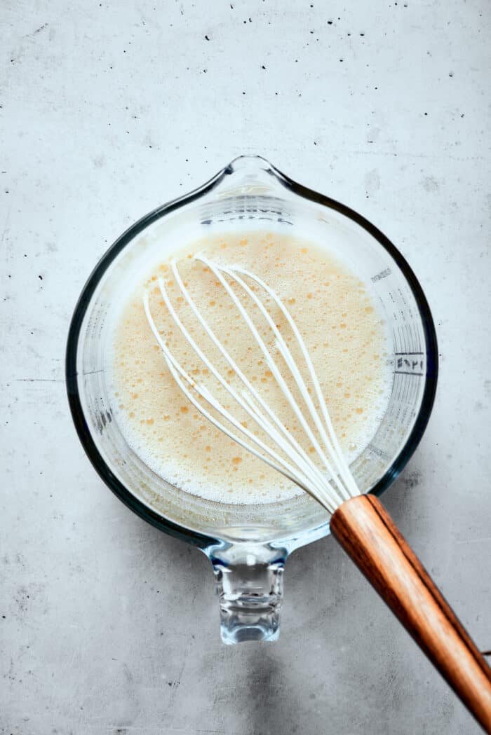 Eggs are whisked in a glass measuring cup.