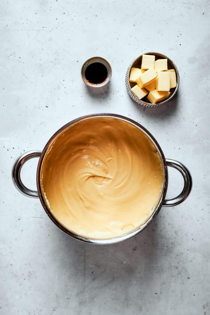 A top down shot of pastry cream with a bowl of cubed butter on the side.