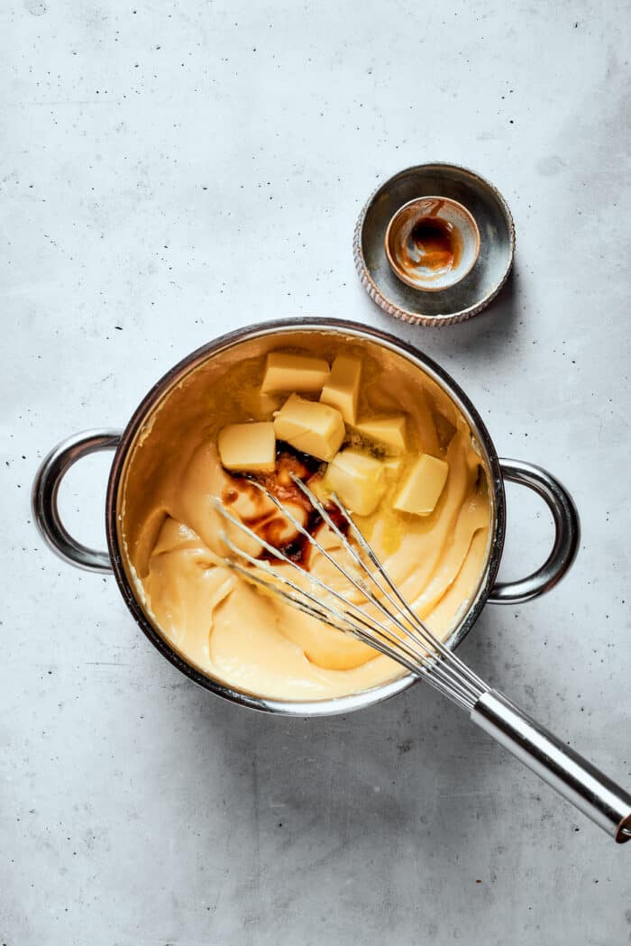 Butter is whisked into a pot of pastry cream.