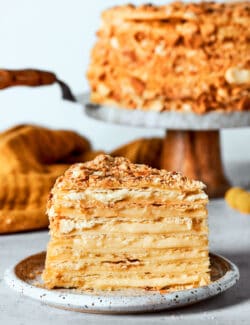 A side view of a piece of Napoleon cake with the cake in the background.