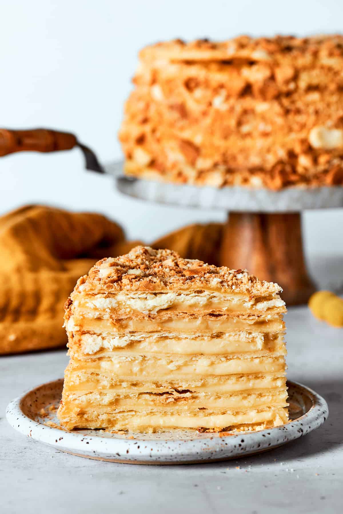 A side view of a piece of Napoleon cake with the cake in the background.