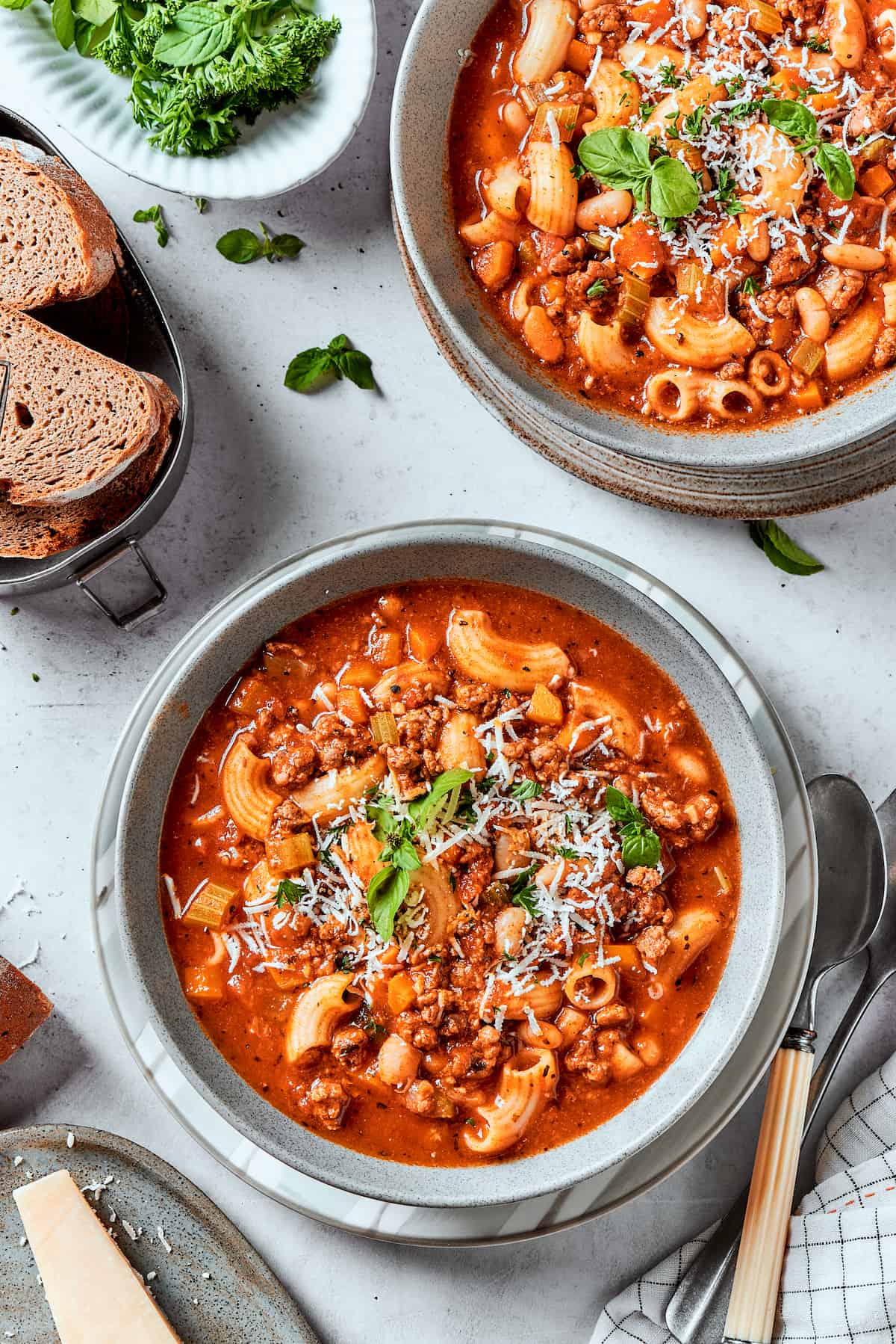 Easy, Italian-inspired Pasta Fazool is a wonderful soup that pairs creamy white beans with ground meat and pasta in a tomato-based broth. A top down shot of bowls of pasta fazool on a table.