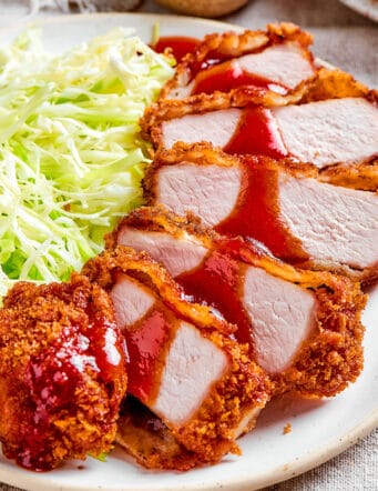 sauce drizzled over sliced pork katsu on a plate