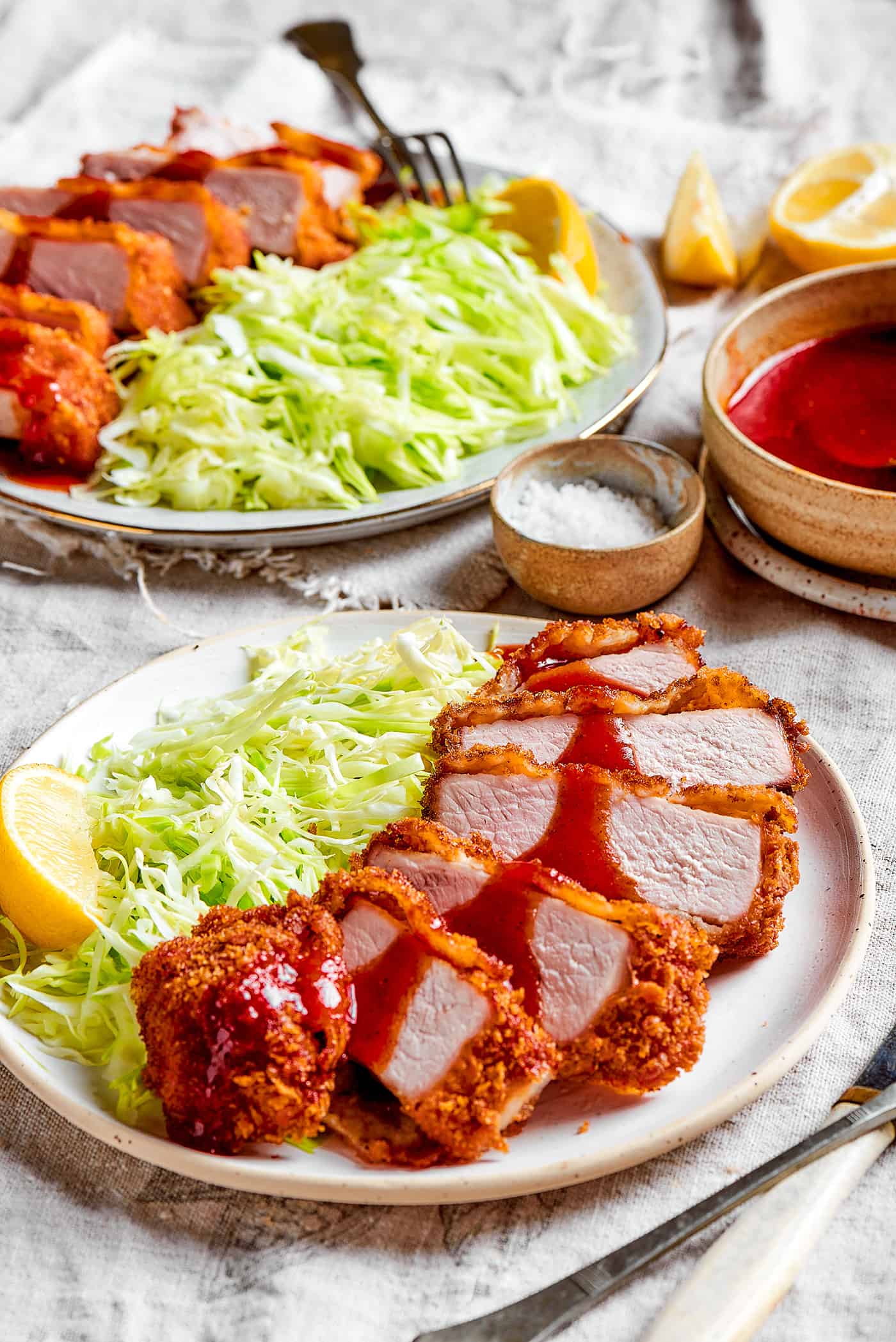 2 plates with sliced pork katsu and cabbage