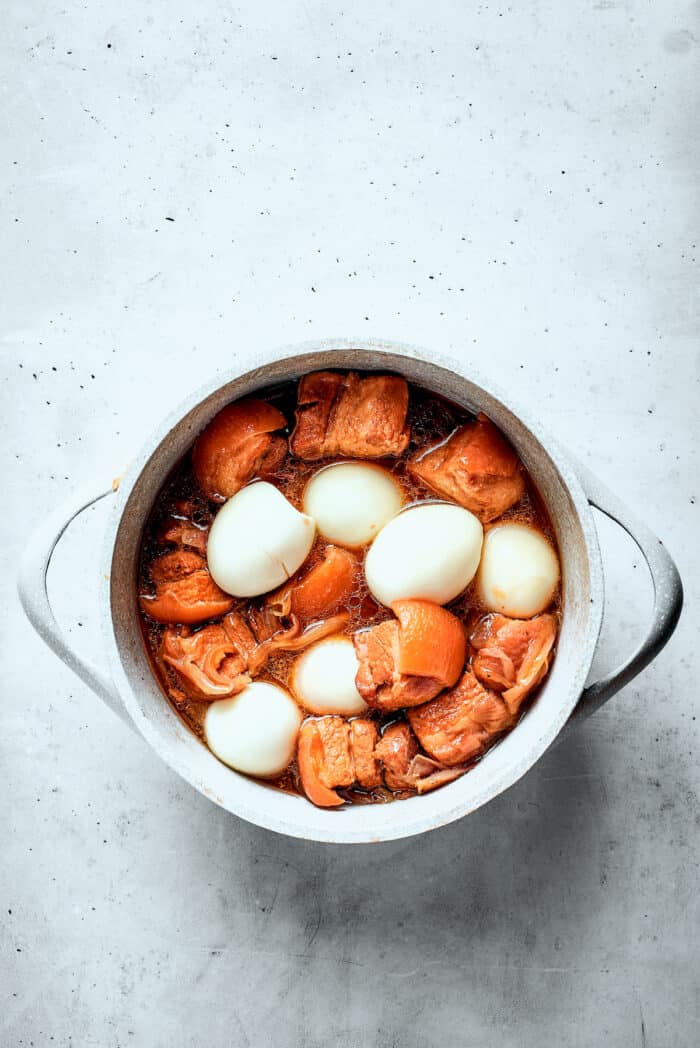 Hard boiled eggs are added to a pot of Thit Kho.