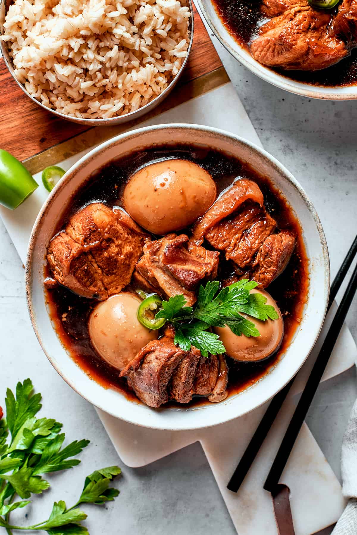 A top down shot of a bowl of Thit Kho with rice next to it.