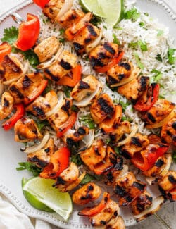 A platter of chipotle honey chicken kabobs is shown with lime wedges.