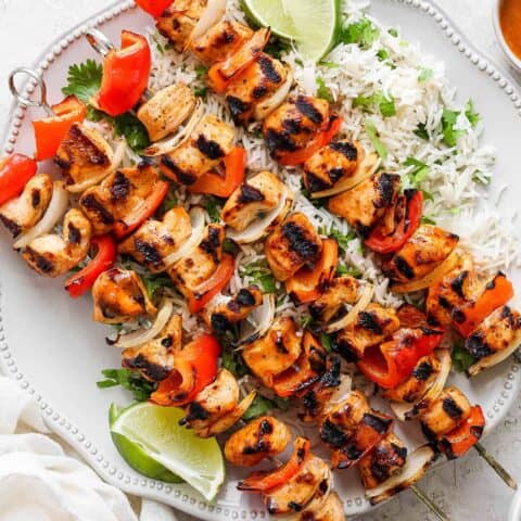 A platter of chipotle honey chicken kabobs is shown with lime wedges.
