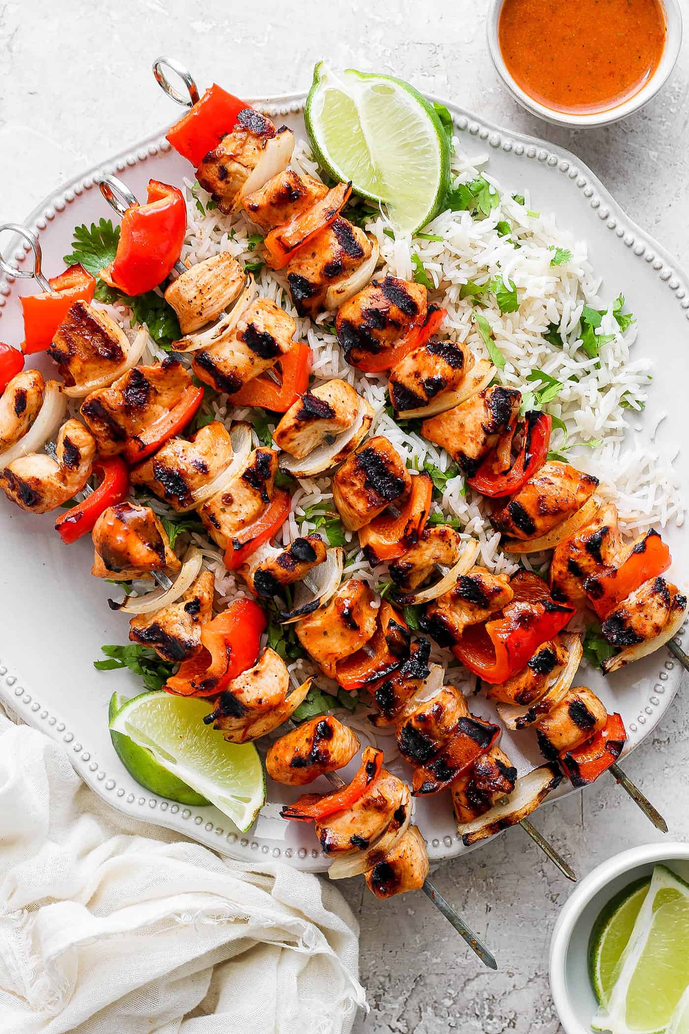 A platter of chipotle honey chicken kabobs is shown with lime wedges.