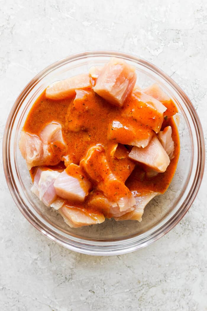 Chicken and vegetables marinate in a glass bowl.