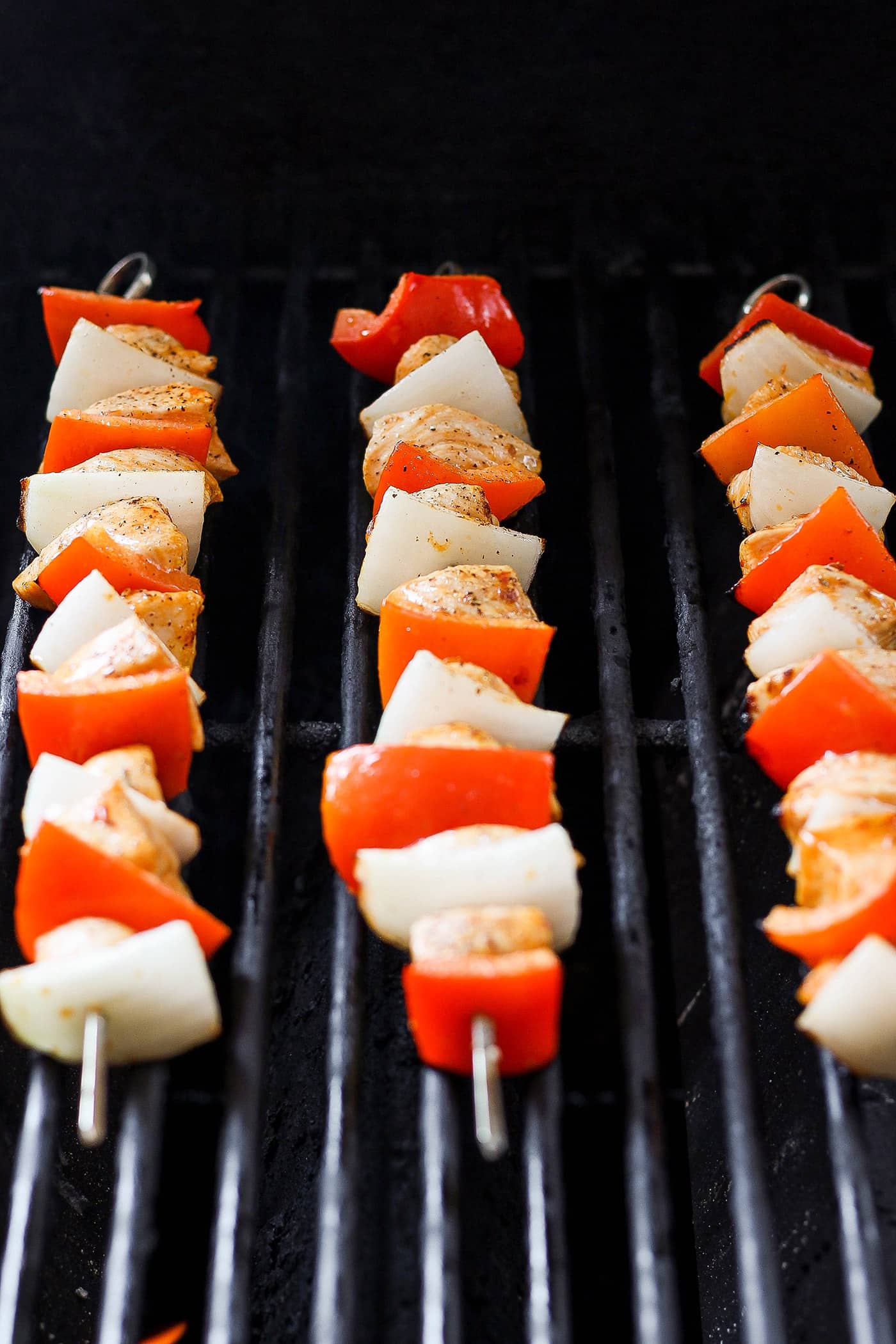 Chipotle honey chicken skewers are shown cooking on the grill.