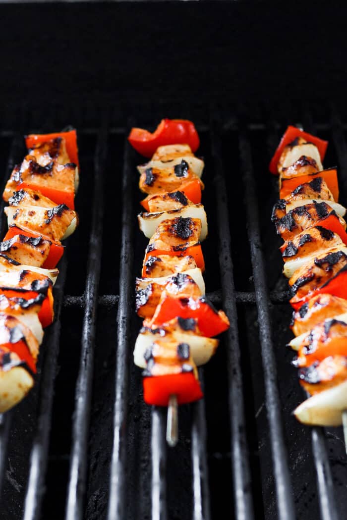 Chipotle honey chicken skewers are shown cooking on the grill.