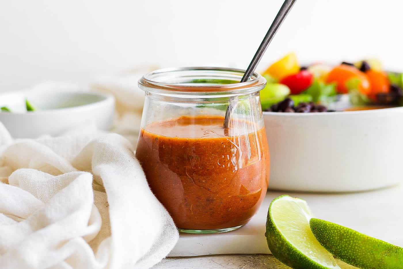 a jar of homemade chipotle honey vinaigrette, plus a bowl of fresh salad