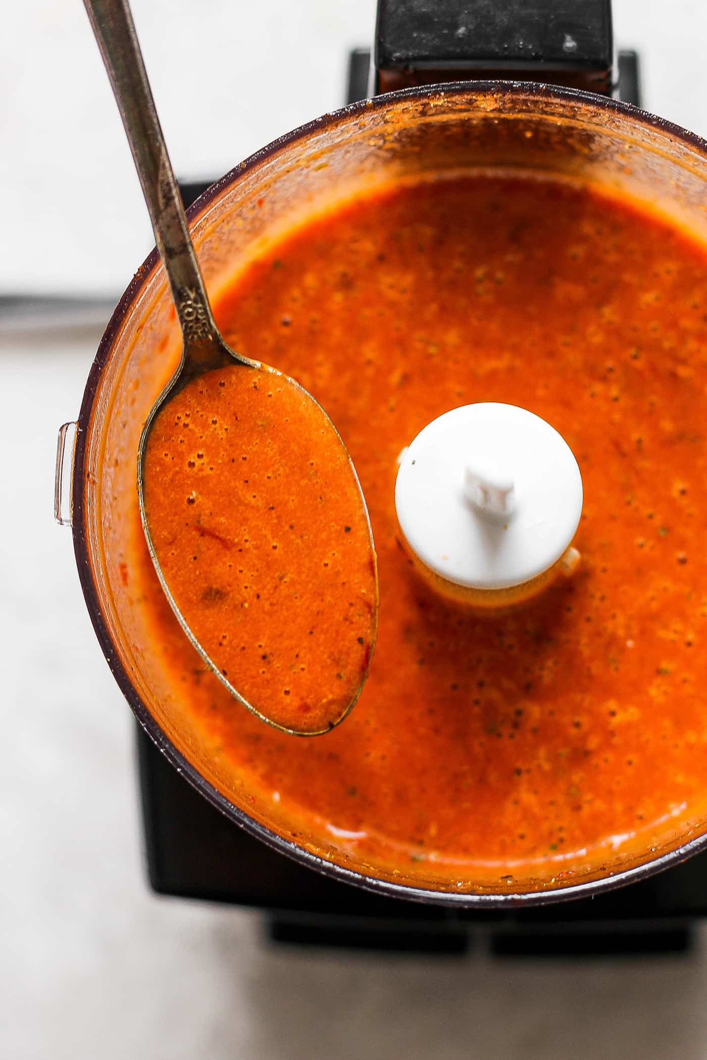 a spoon showing the consistency of chipotle honey vinaigrette, straight from the food processor bowl