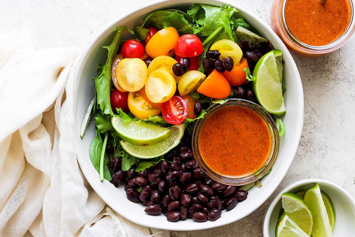 overhead photo of a fresh salad with black beans and salad dressing