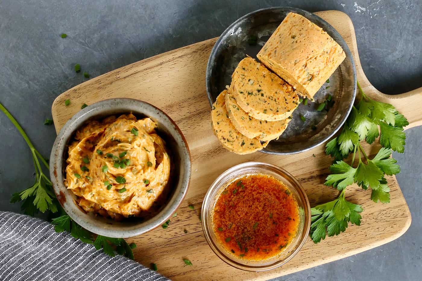 Cowboy butter on a wooden board, shown 3 different ways: in a bowl, formed into a log, and melted