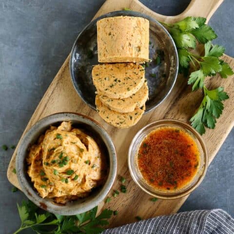 Cowboy butter on a wood board, shown 3 different ways: in a bowl, formed into a log, and melted