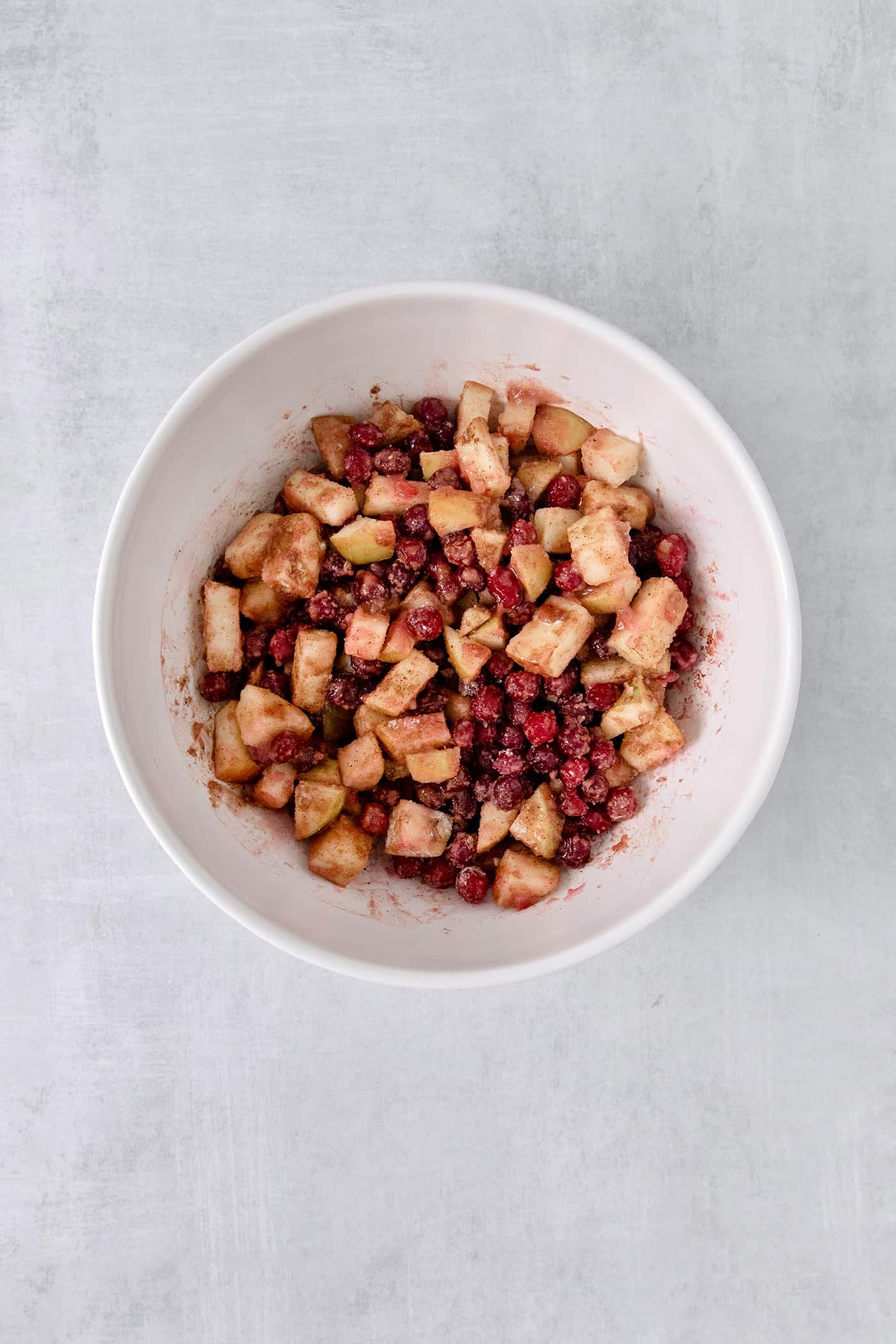 A white bowl of cranberry apple crisp filling.